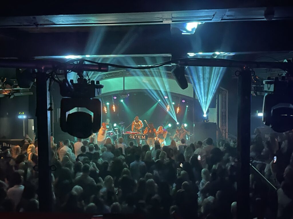 Crowd in front of a stage with a moving-head light and green beams
