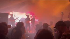 Aband playing on a stage with a video wall behind them siloutting them.