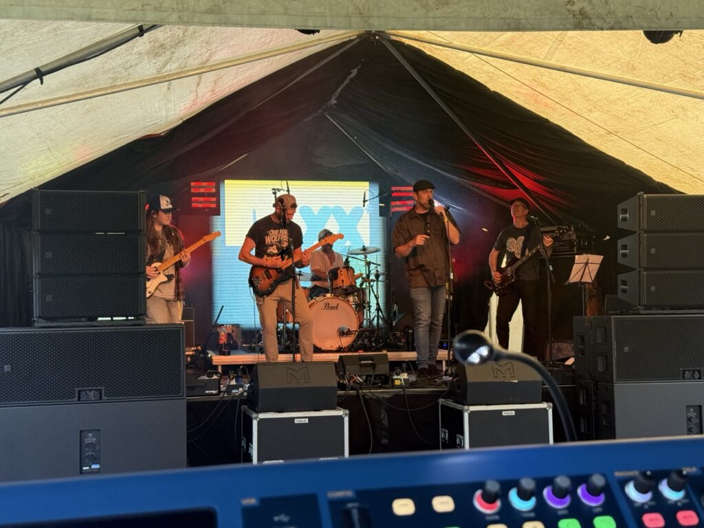 Band on stage with an LED screen behind them and the mixing desk in the foreground