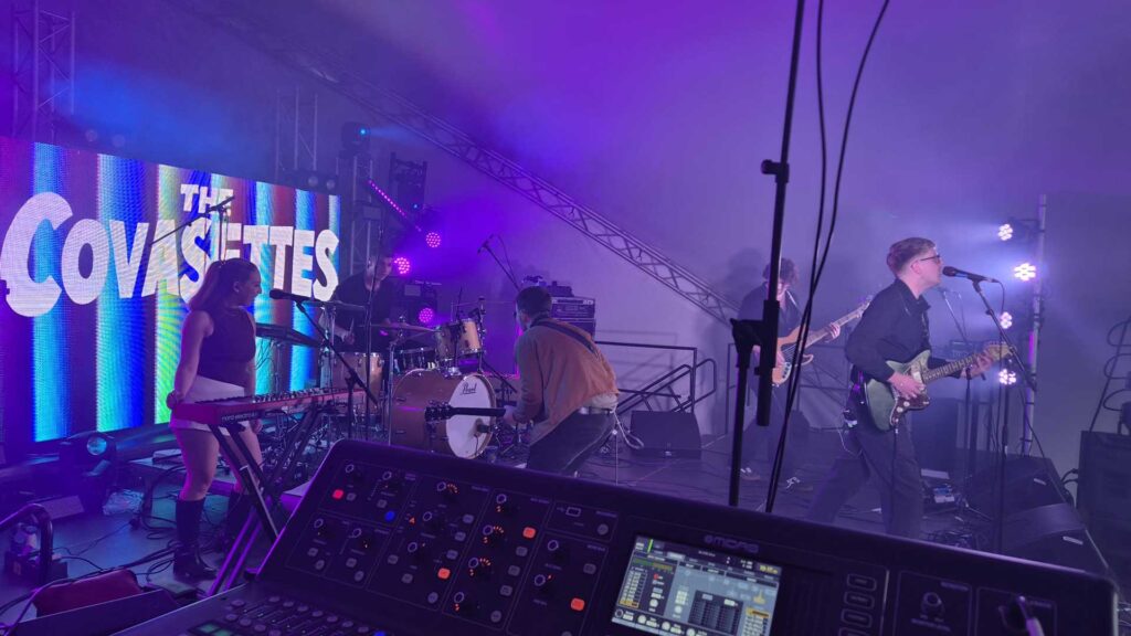 Band playing on a purple and blue stage with a screen behind them at Loopfest