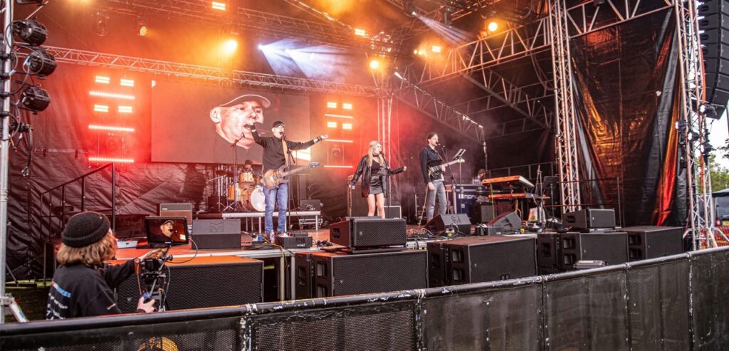Stage with orange and red lighting and monitor wedges along the front at Meadowfest