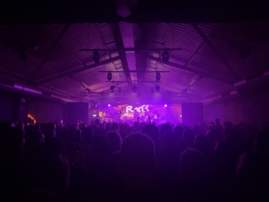 Orchestra performing on a purple-lit stage in a dark hall