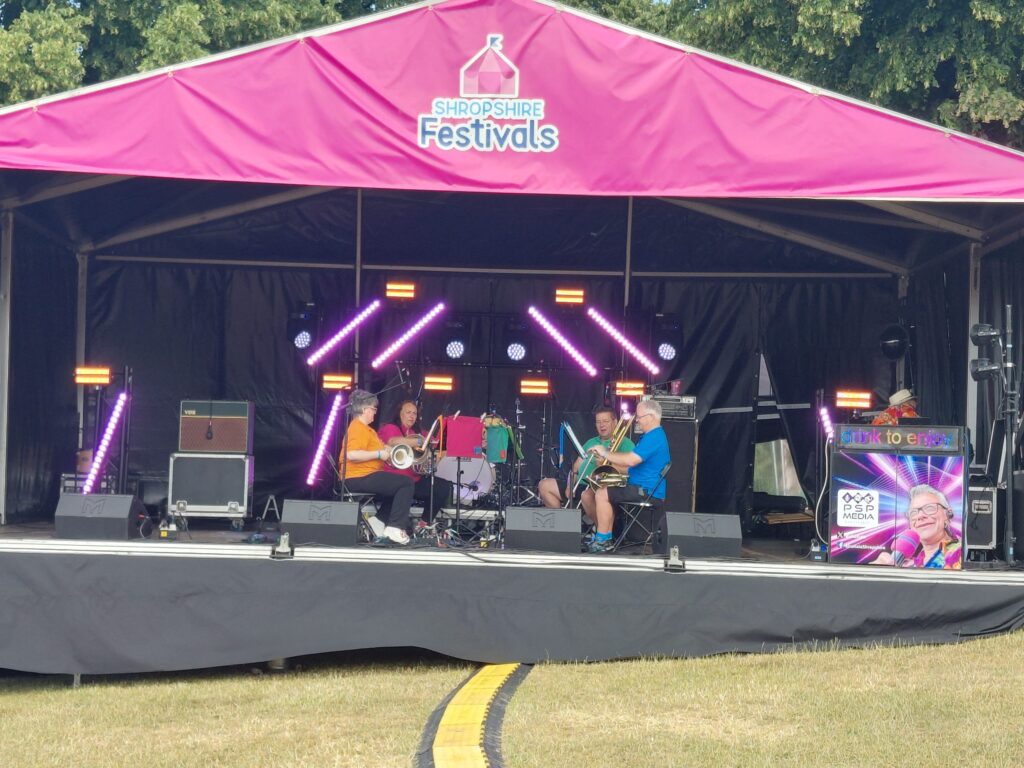 Pink-canopied stage with a band playing and a lighting rig above