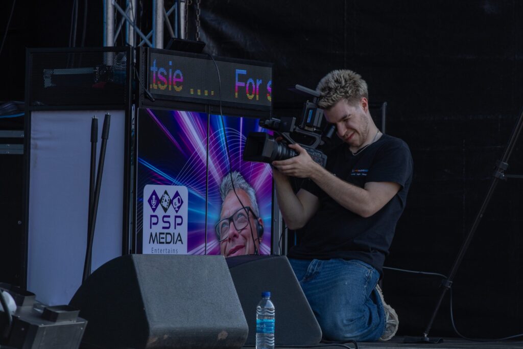 Camera operator filming beside a lit stage