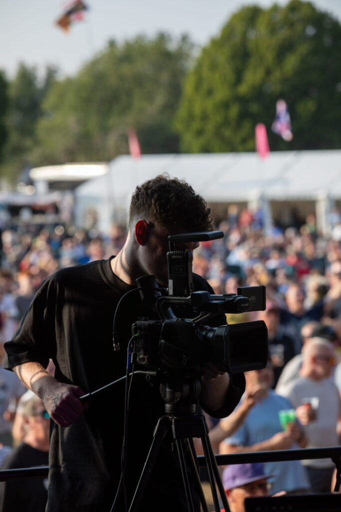 Camera operator at a tripod filming the crowd at a summer event