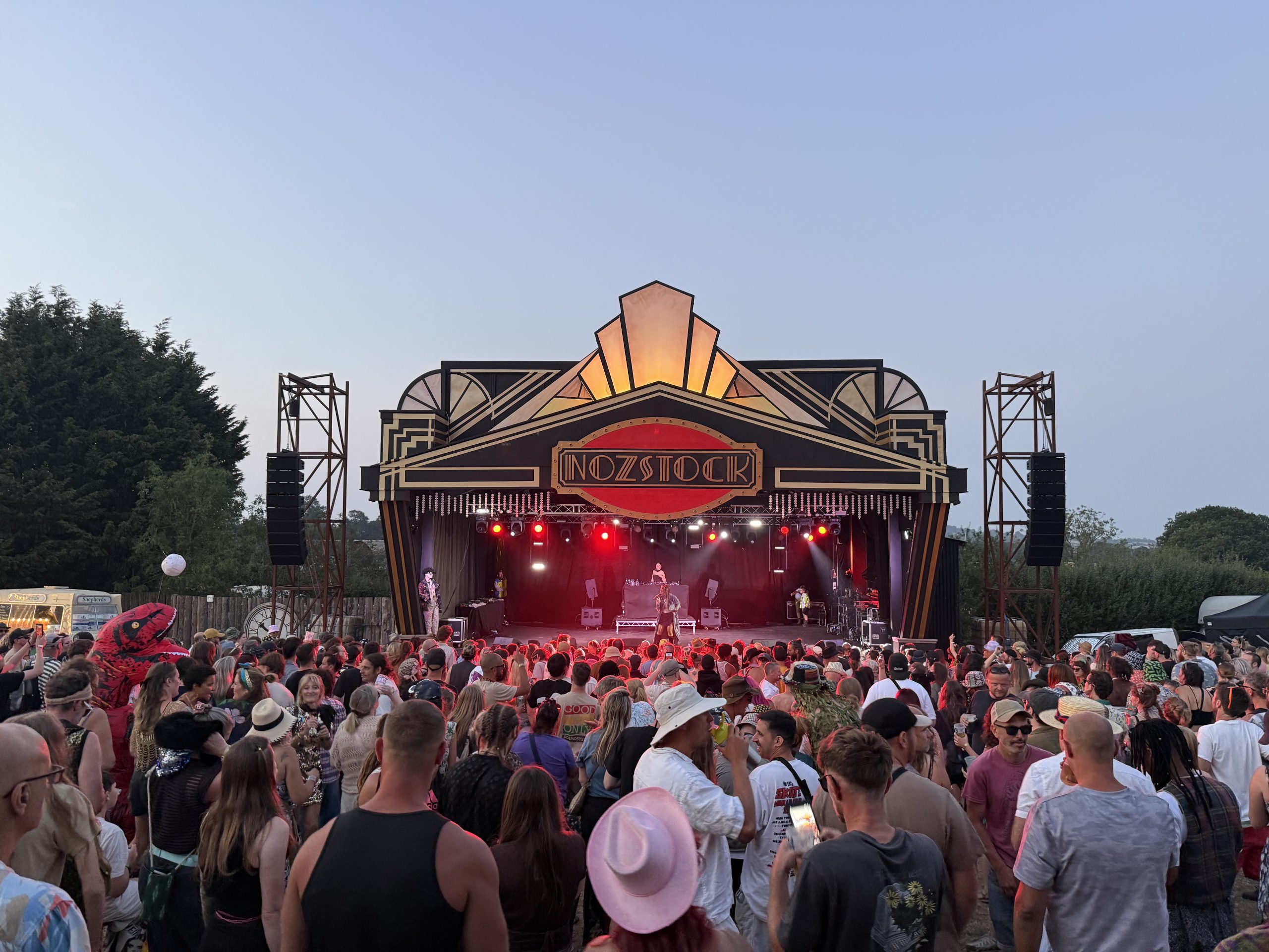 A large audience of people watch Eva Lazaras sing on a stage. Lights from the stage shine out behind her .