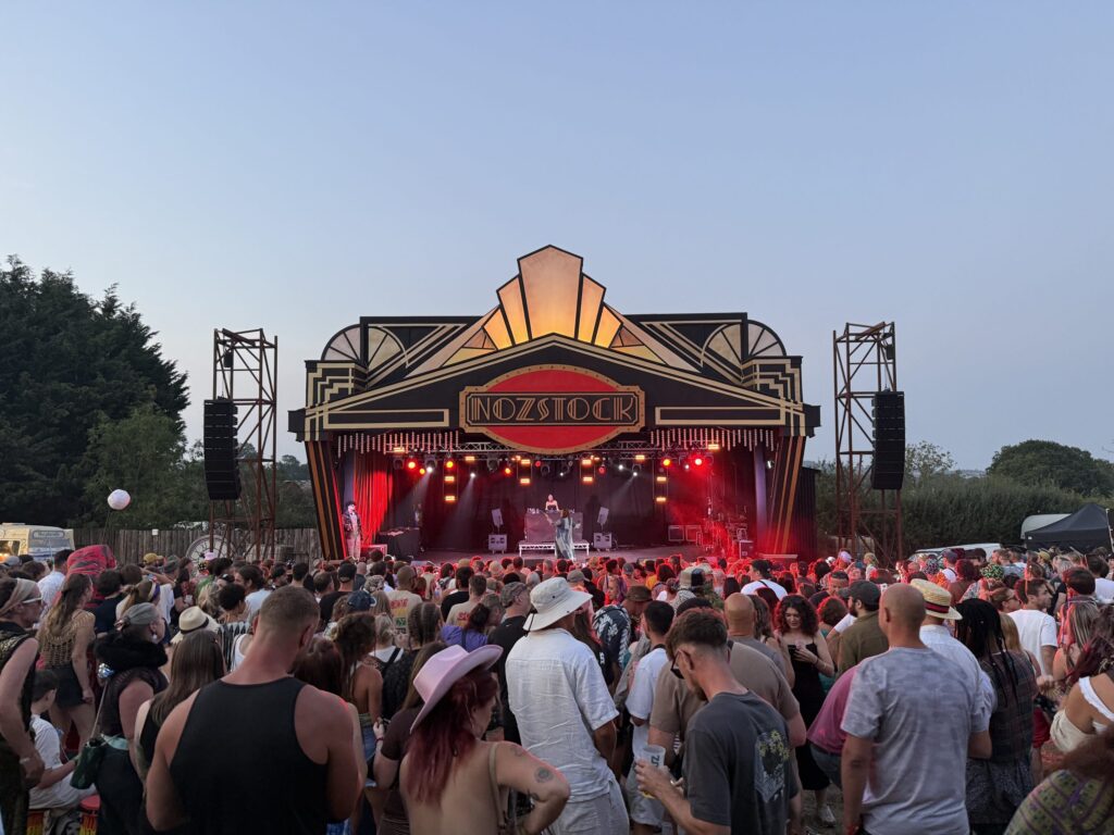 Crowd watching a singer on the main stage at Nozstock 2026, with stage lights shining out over the audience