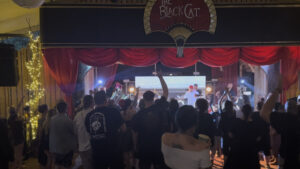 Band on the marquee stage with a red backdrop and an audience watching