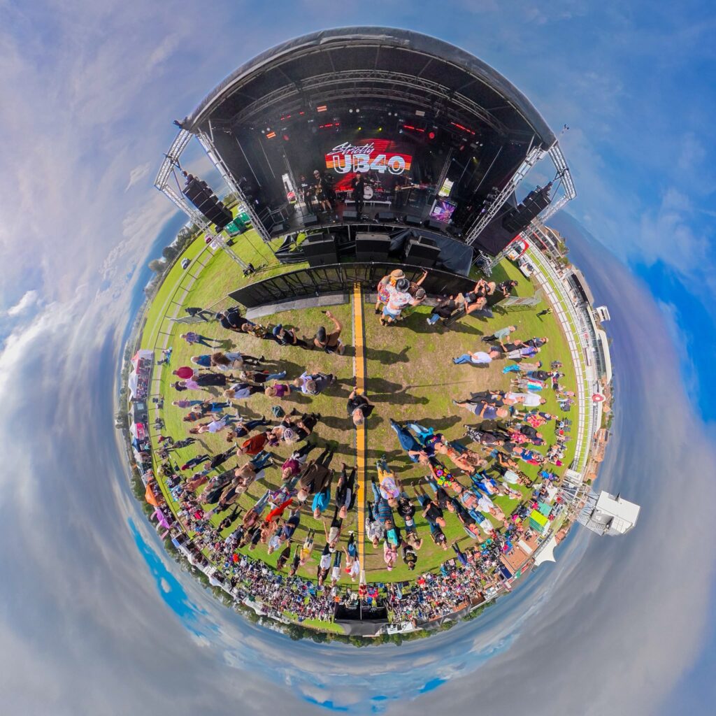 Fisheye view of a festival field curling around the stage and crowd