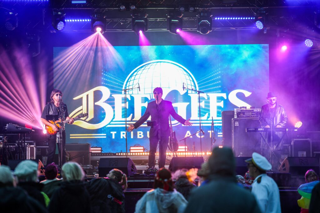 Tribute band playing on stage in front of a large LED screen