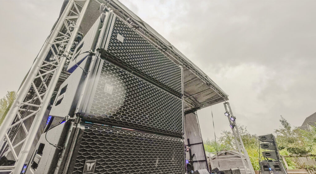 Truss and a flown speaker array rigged under a roof, seen from below