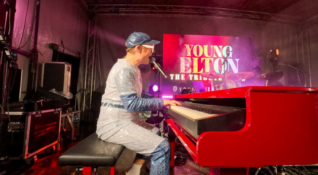 Pianist playing a red piano on stage under red lighting
