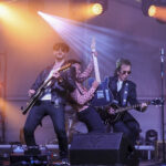Two guitarists on stage at Oktoberfest 2026 under orange and blue lighting, supported by our full event production package