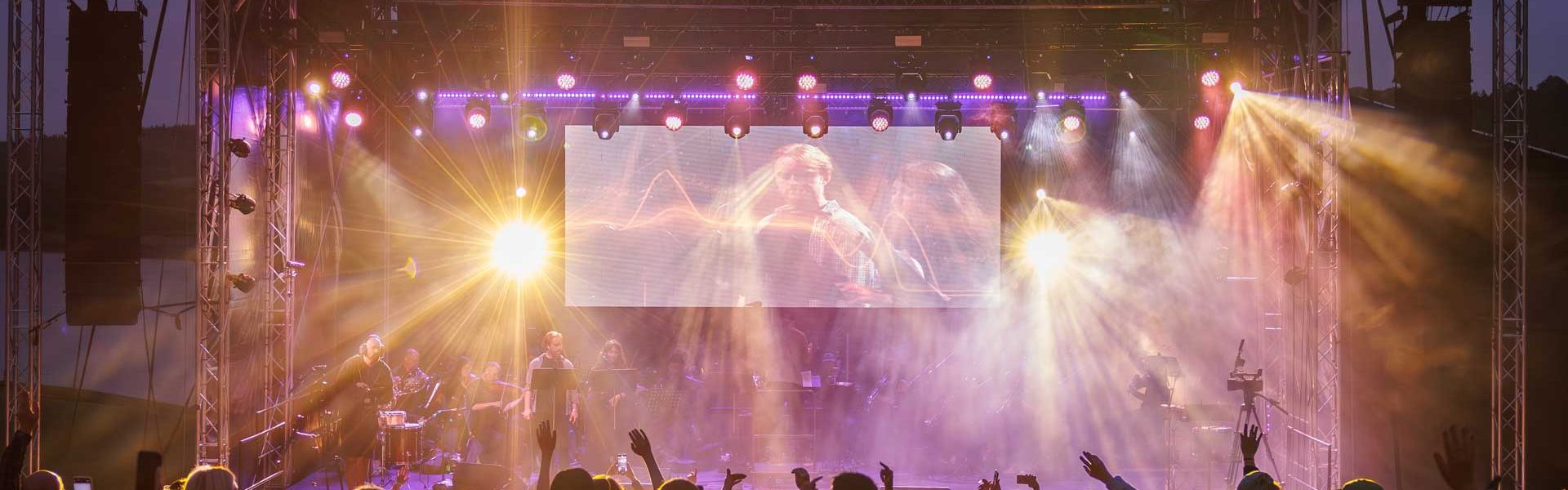 Live event stage with colourful beam and wash lighting above the crowd