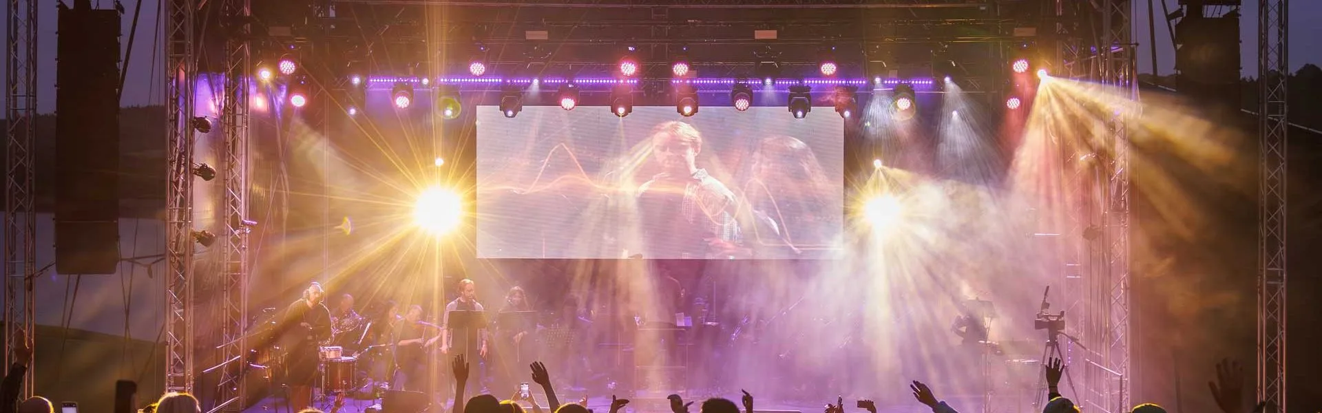 Live event stage with colourful beam and wash lighting above the crowd