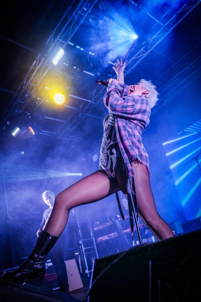 Singer with her head tilted back on a blue-lit stage